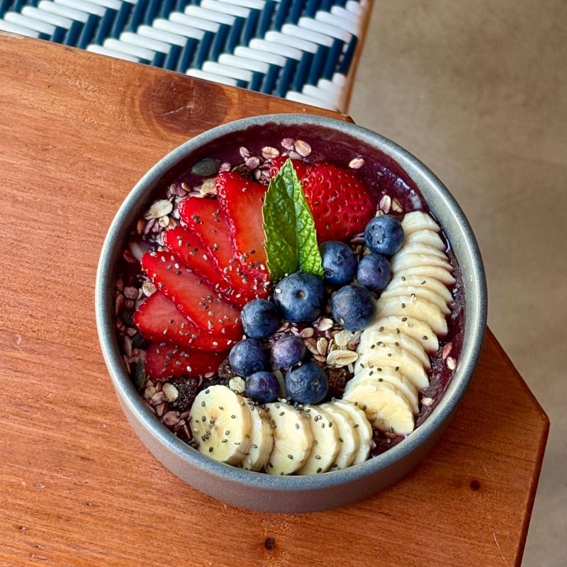 Plano contrapicado de bowl de helado de açaí bien fresquito, decorado por frutas frescas finamente cortadas y arándanos.